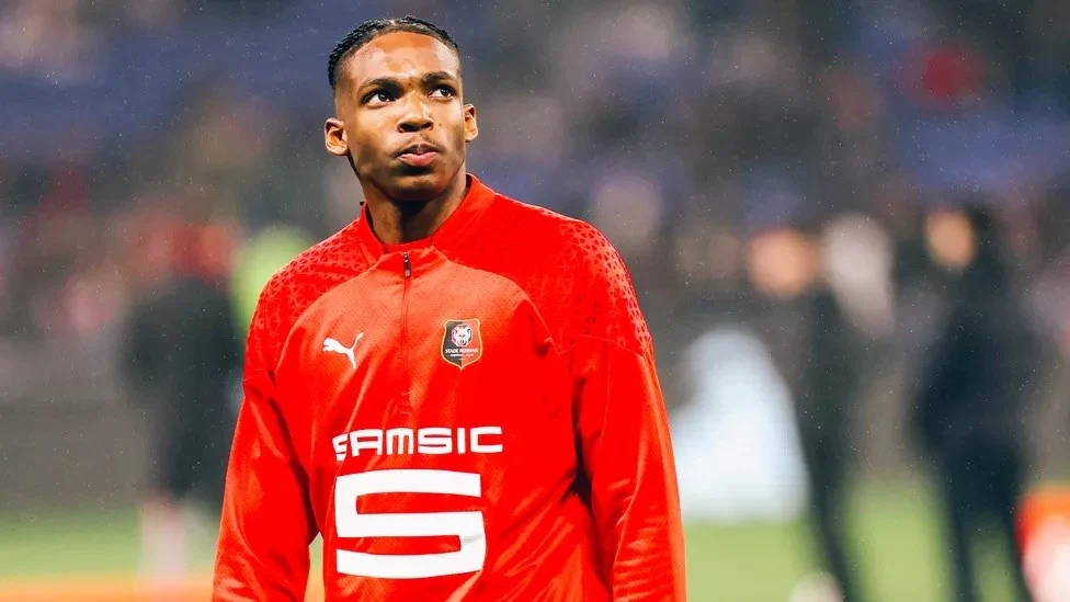 Cầu thủ Jacquet mặc áo đấu màu đỏ của Rennes trong thời tiết mưa.